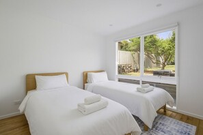 A hotel room with two beds, white bedding, a large window with a view of the outdoors, and a wooden floor. - The Sandman (McCrae)
