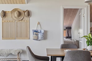 Una habitació amb un mur de llistons de fusta, una banca, una taula i una porta que dona a una altra habitació.