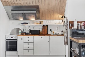 Eine moderne Küche mit weißen Schränken, einem Einbauofen, einer Mikrowelle und einer Kaffeemaschine.