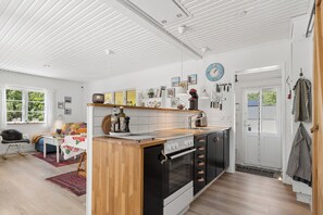 Una cocina moderna con una isla de madera, electrodomésticos negros y blancos y un techo blanco.