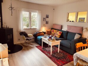 Una sala de estar acogedora con un sofá, una butaca, una mesita de centro y una chimenea.