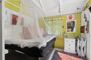 Ein Schlafzimmer mit einem Himmelsbett, einem Schminktisch, einem Heizkörper und einem Spiegel an der Wand.
