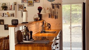 A kitchen with wooden countertops, a sink, a kettle, and various kitchen utensils hanging on the wall.