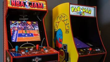 Deux bornes d’arcade, l’une pour le jeu NBA JAM et l’autre pour Pac-Man, avec une enseigne au néon au-dessus.