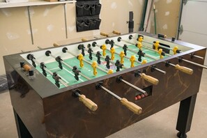 A foosball table with a green playing surface, black and yellow player figures, and wooden handles.