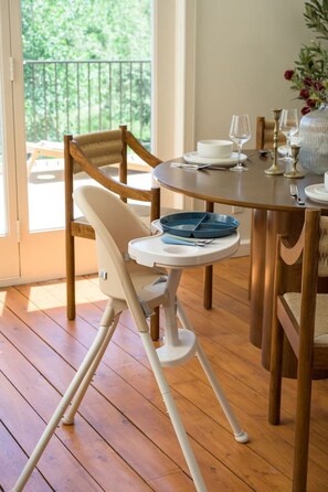 A dining area with a wooden table, chairs, and a high chair.