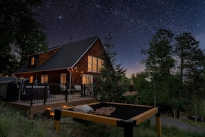 A cabin with a deck, a bed, and a starry night sky.