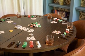 A round table with poker chips, playing cards, and glasses of whiskey.