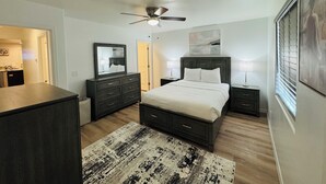 Ein Schlafzimmer mit Bett, Schminktisch, Nachttischen, Deckenventilator und Teppich.
