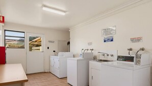 Ein Waschraum mit Waschmaschinen, Trocknern, einem Waschbecken und einem Tisch.
