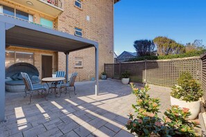 A covered patio with outdoor seating, a brick building, and a wooden fence. - Sea Blue Retreat 2-Bed Unit in Glenelg North (Glenelg North)