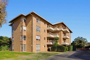 A multi-story apartment building with a brick facade, balconies, and a paved driveway. - Sea Blue Retreat 2-Bed Unit in Glenelg North (Glenelg North)