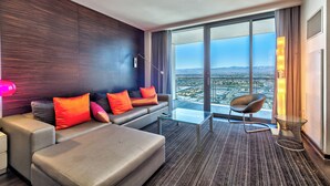 A modern hotel room with a sofa, a glass coffee table, a chair, and a large window offering a city view. - Cozy studio with AC in serene Las Vegas location (Las Vegas)