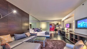 A modern living room with a sofa, a coffee table, a TV, and a kitchen area in the background. - Cozy studio with AC in serene Las Vegas location (Las Vegas)