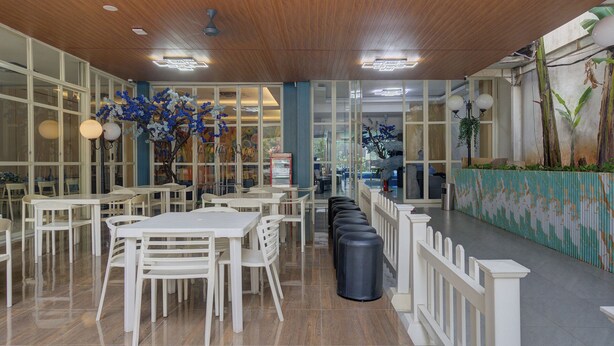A restaurant with white tables and chairs, a wooden ceiling, and decorative plants. - Hotel Bunga-Bunga By ARBA (Jakarta)