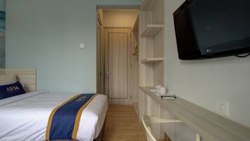 Habitación de hotel con cama, televisión, armario y una pequeña mesa con tazas.