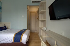 Een hotelkamer met een bed, een televisie, een kledingkast en een klein tafeltje met kopjes.