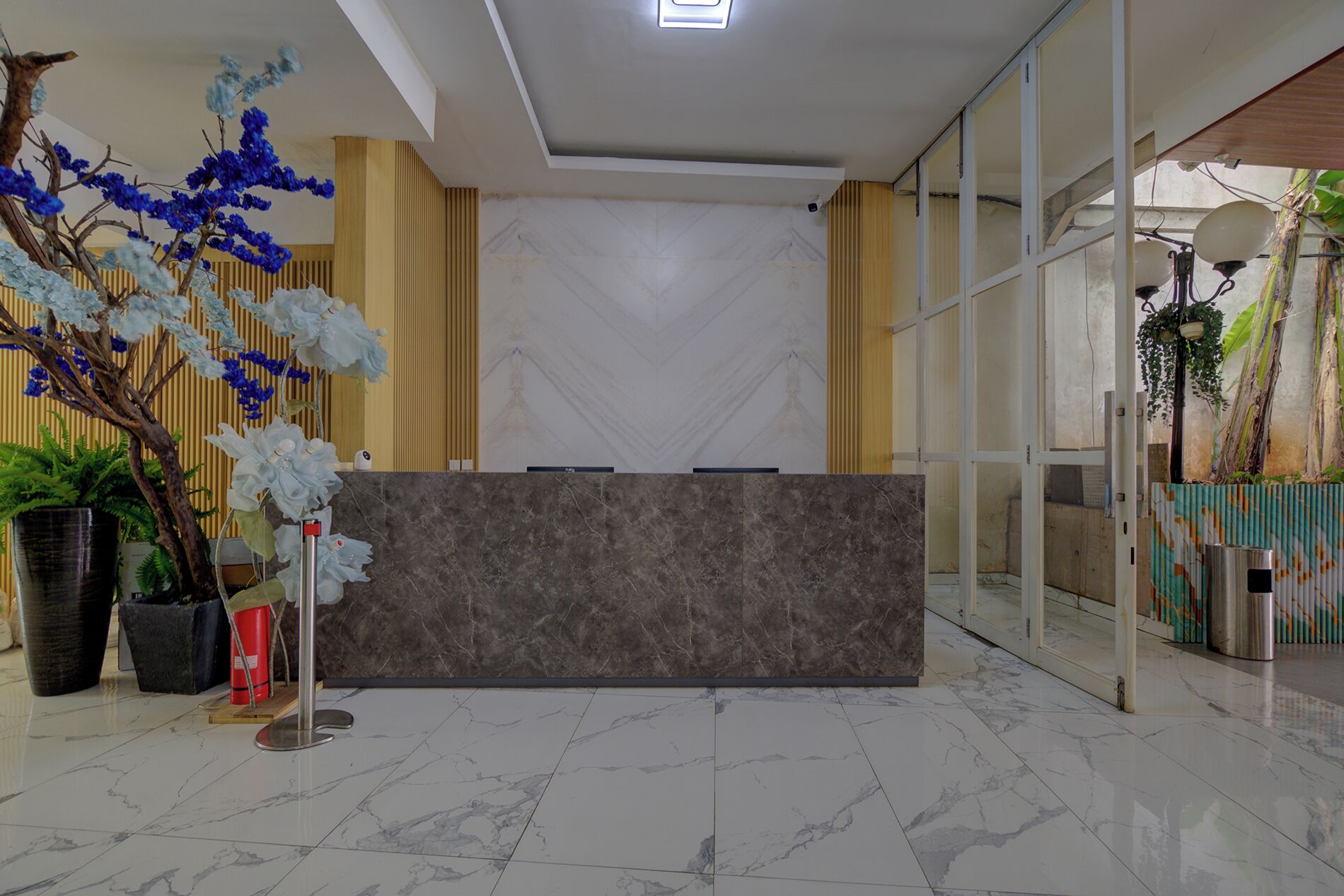 A reception area with a marble-tiled floor, a reception desk, and decorative plants.