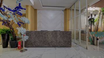 A reception area with a marble-tiled floor, a reception desk, and decorative plants.