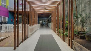 A corridor with wooden columns, a white picket fence, and potted plants. - Hotel Bunga-Bunga By ARBA (Jakarta)