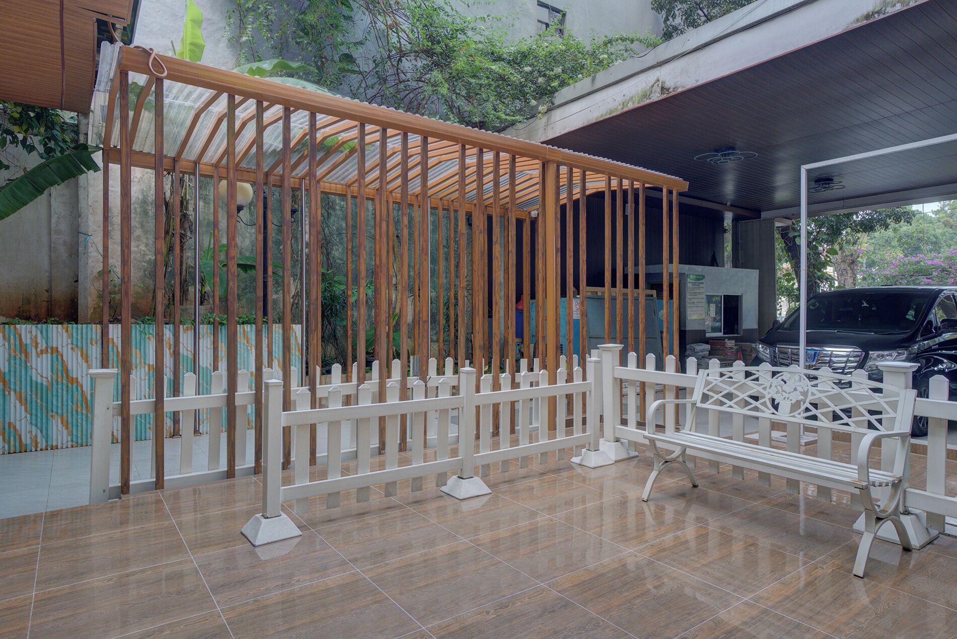 A covered outdoor area with a wooden structure, white fence, and a bench.
