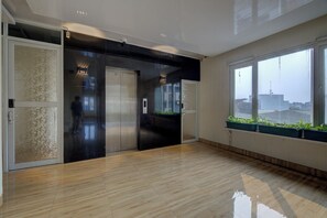 A modern interior with a sliding door, a glass elevator, and a large window with a view. - Hotel Bunga-Bunga By ARBA (Jakarta)
