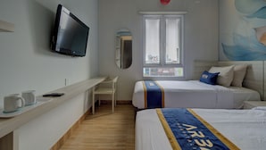 A hotel room with a bed, a desk with a computer, a television, and a window with a view of buildings. - Hotel Bunga-Bunga By ARBA (Jakarta)