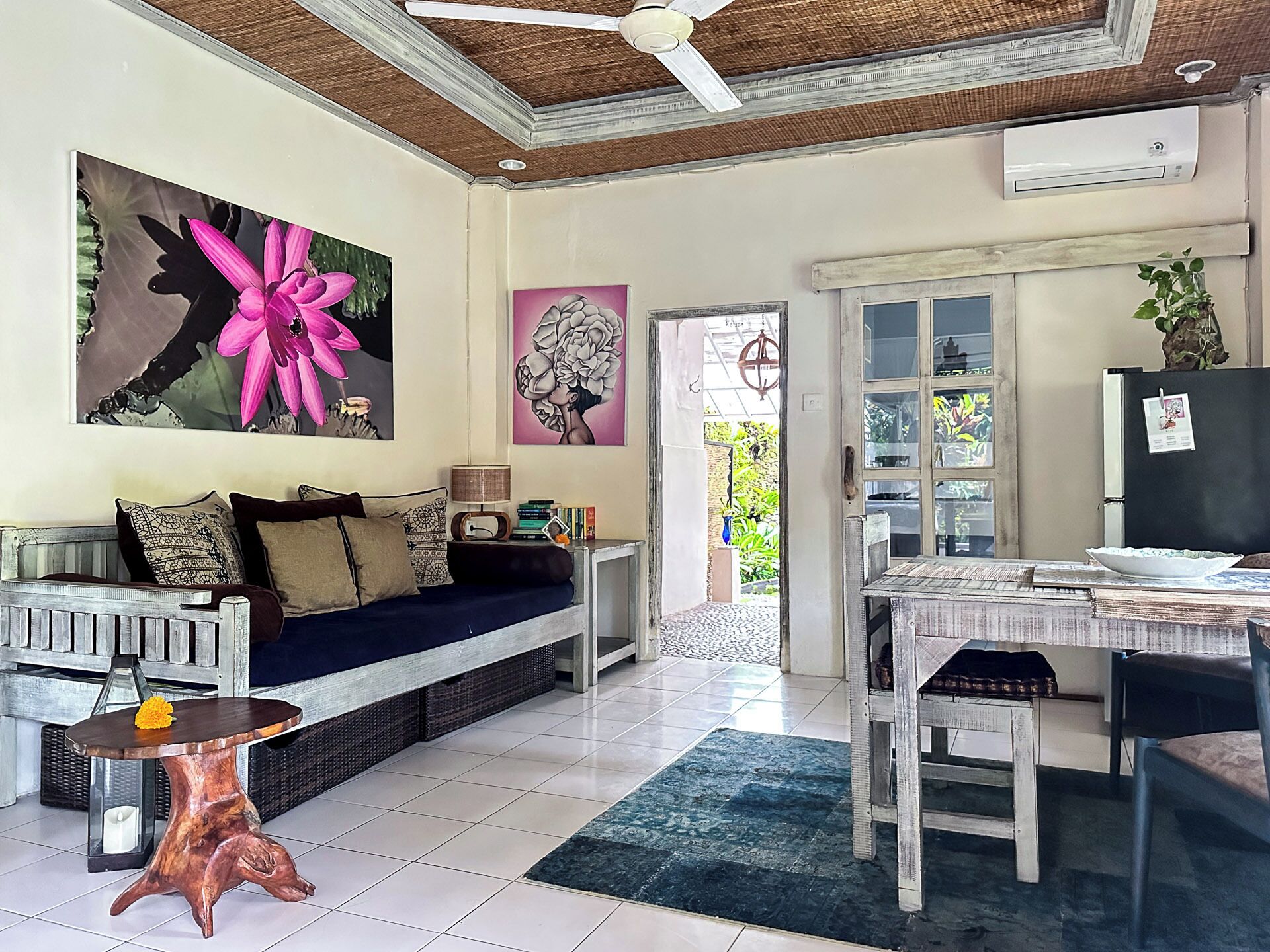 Sala de estar con sofá, mesa de centro, mesa de comedor y una zona de cocina con alacenas y refrigerador.