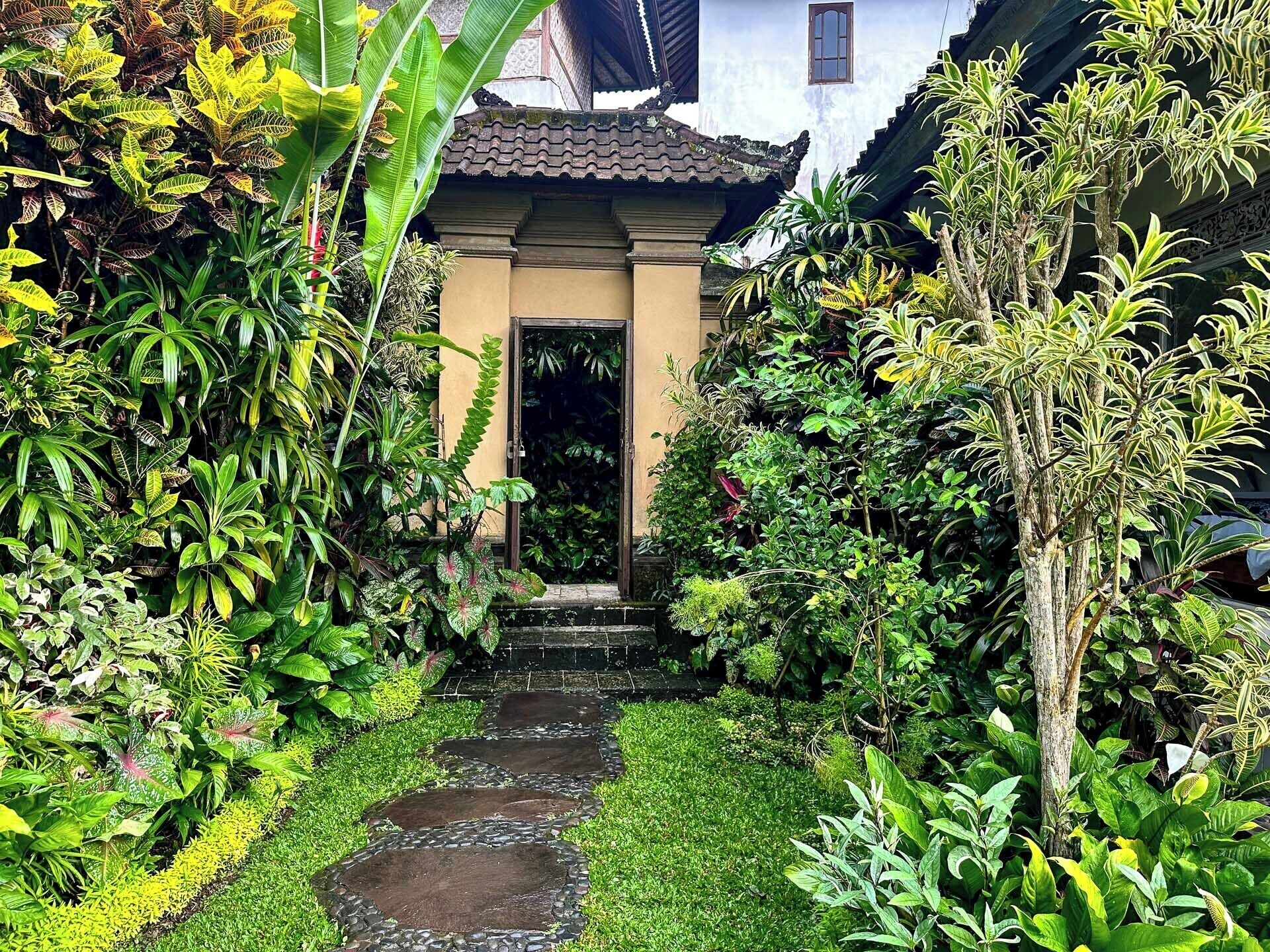 Un sendero en un jardín que lleva a un edificio con techo de tejas y una puerta.