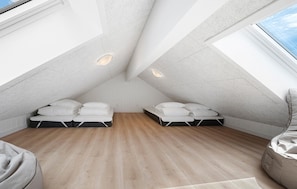 Ein Schlafzimmer im Dachgeschoss mit hohen Decken, zwei Betten, Holzboden und Dachfenstern.