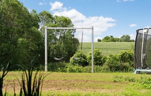 Ein Garten mit Schaukel, einer Wiese und einem Zaun.