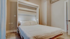 A bedroom with a bed, a built-in shelf unit, and a door. - Family Surf Villa with Resort Amenities at Venao (Las Escobas del Venado)