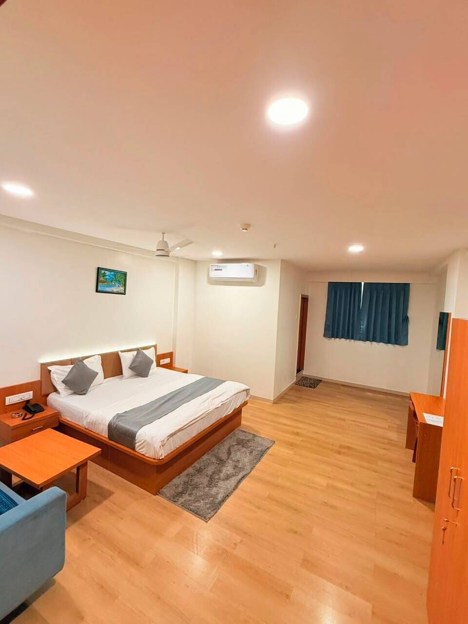 A hotel room with a bed, bedside table, and a desk.