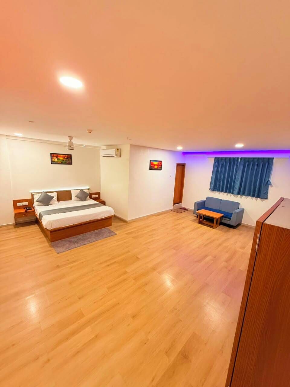 A bedroom with a bed, bedside tables, a sofa, a small table, and a window with curtains.