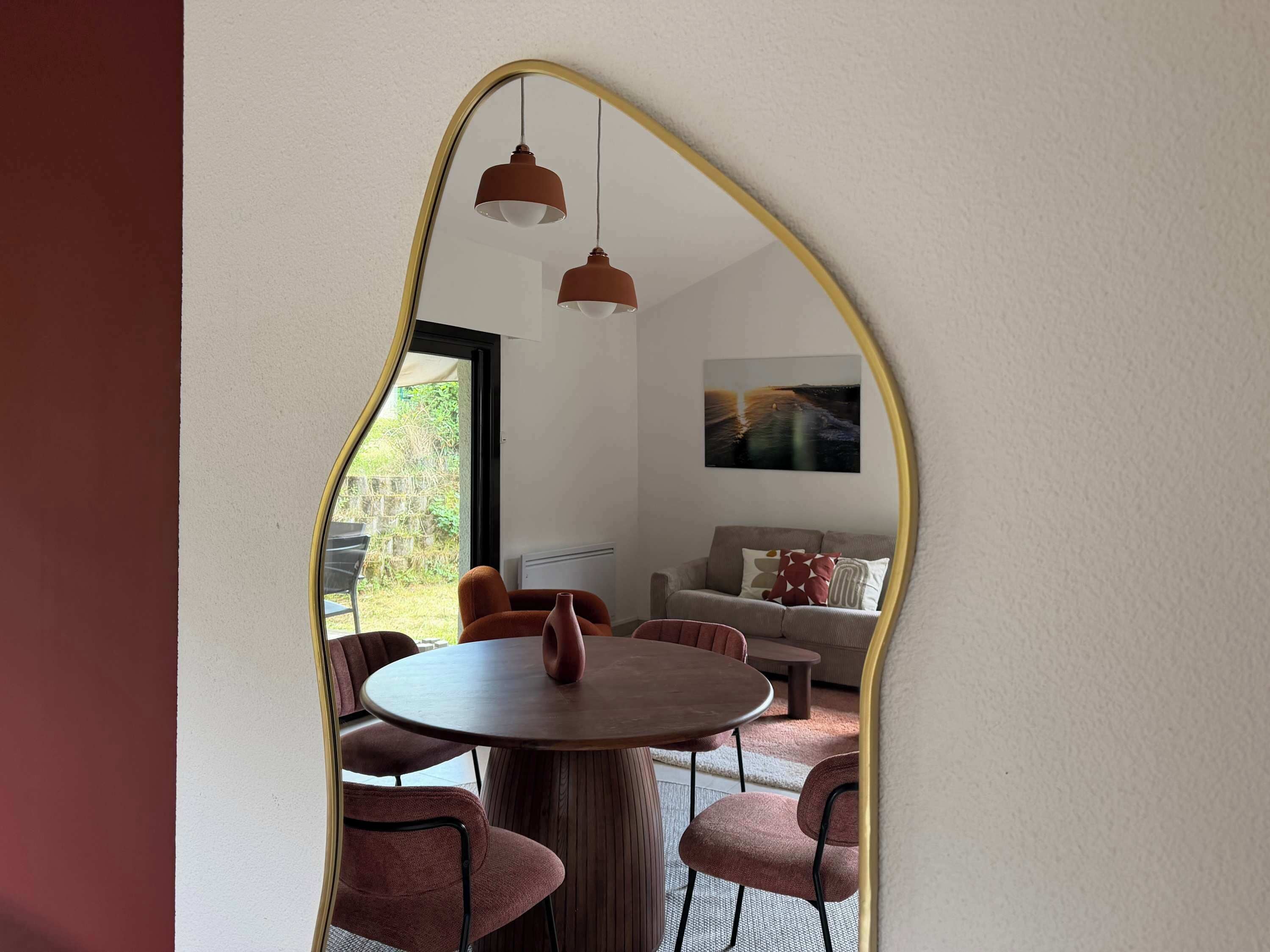 A dining area with a round table and chairs, a sofa, and a painting on the wall.