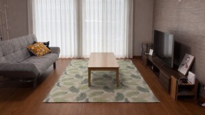 Un salon avec un canapé, une table basse, un téléviseur et un tapis à motifs.