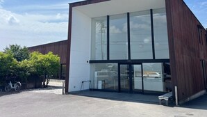 Un bâtiment moderne doté d’une grande façade en verre, d’un revêtement extérieur en bois et surplombant un ciel dégagé.