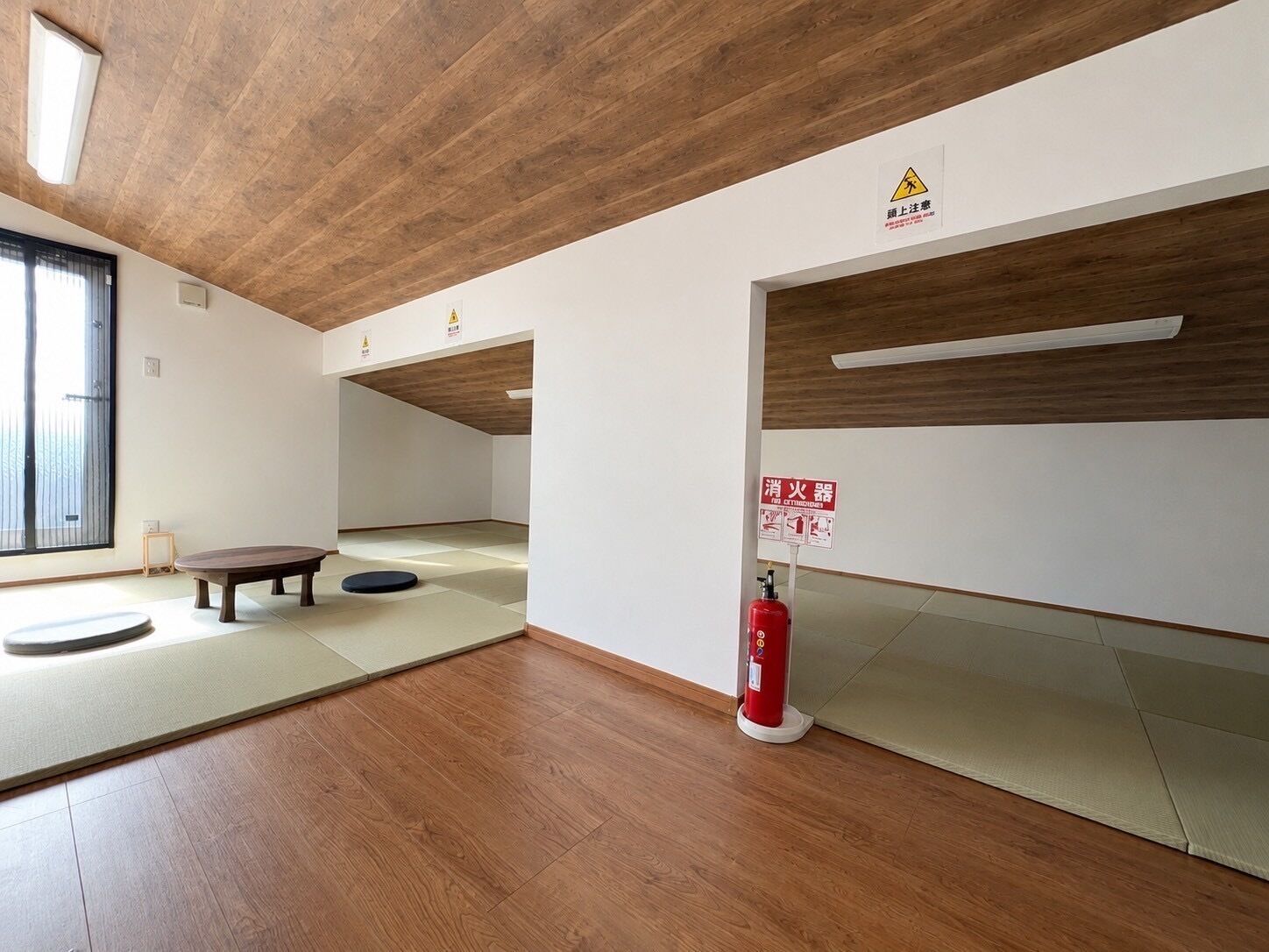 Una stanza con tatami, soffitto in legno e estintore.
