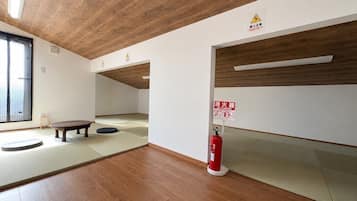 Una stanza con tatami, soffitto in legno e estintore.