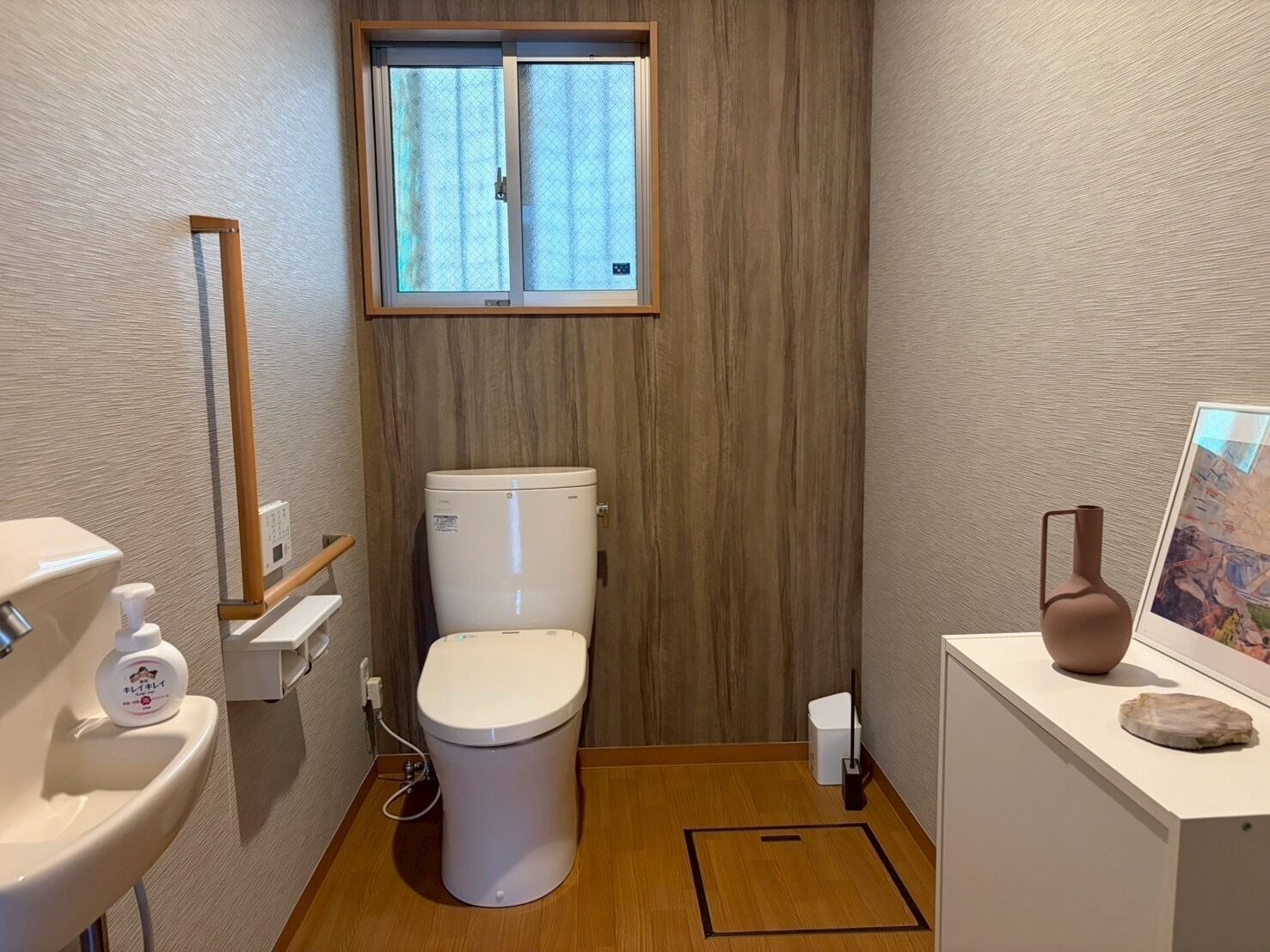 A compact bathroom with a toilet, sink, and a small window above the toilet.