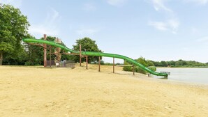 Ein Sandstrand mit einer grünen Rutsche.