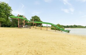 Ein Sandstrand mit einer grünen Rutsche.
