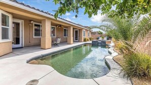Ein Wohnhaus mit Swimmingpool, Sitzgelegenheiten im Freien und einer überdachten Terrasse.