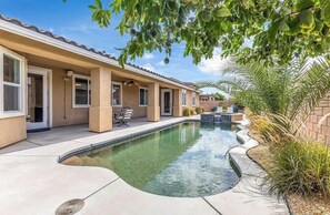 Ein Wohnhaus mit Swimmingpool, Sitzgelegenheiten im Freien und einer überdachten Terrasse.