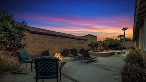Eine Terrass mit Feuerstelle, Stühlen und Blick auf den Sonnenuntergang.
