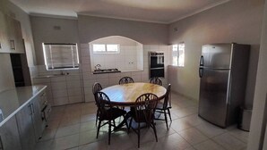 A kitchen with a round dining table, chairs, a refrigerator, and a stove.