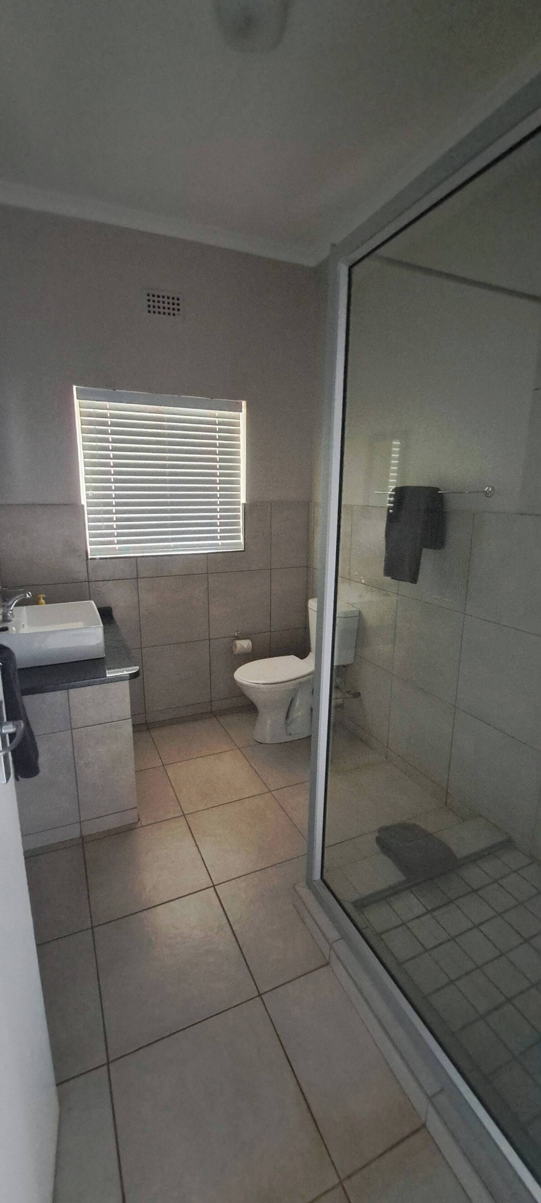 A bathroom with a toilet, sink, and a glass shower enclosure.
