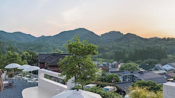 A rooftop terrace with outdoor seating and a large umbrella, overlooking a mountainous landscape.
