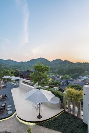 A rooftop terrace with outdoor seating and a large umbrella, overlooking a mountainous landscape. - Hangzhou West Lake MingBai Villa (Hangzhou)