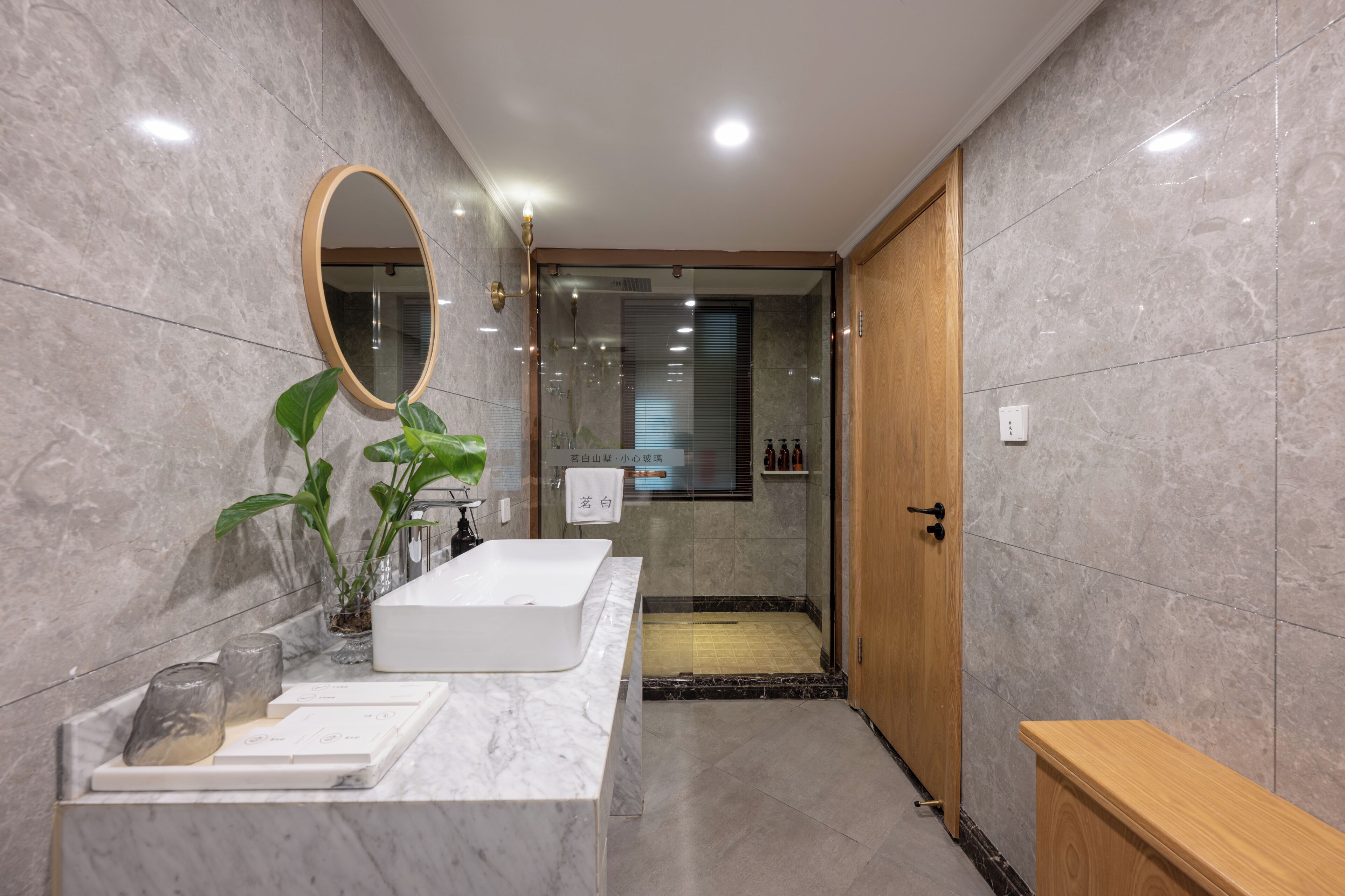 A modern bathroom with a marble vanity, a large mirror, and a shower area.